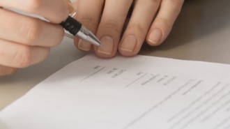 Two People Signing A Document