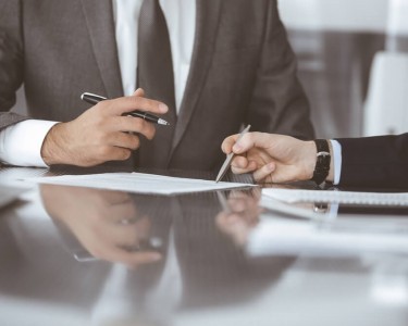 Unknown business people working together at meeting in modern office, close-up. Businessman and woman with colleagues or lawyers discussing contract at negotiation